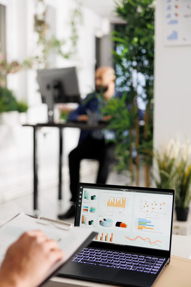 Founder working at a standing desk with a laptop showing sales dashboard data and outbound campaign analytics